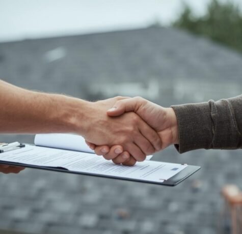 A homeowner and a roofing contractor shaking hands over a clipboard with a lien waiver form, with a newly shingled roof visible in the background.