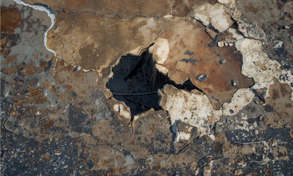 A close-up view of a severely damaged, aged commercial flat roof showing extensive cracked, peeling membrane and visible structural decay, illustrating conditions where a roof coating is not effective and full replacement is required.