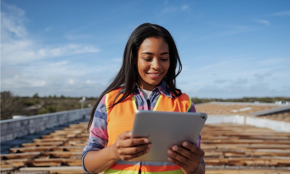 A roofing contractor reviews cost estimates on a tablet with a building owner during a commercial roof replacement project in sunny Florida.