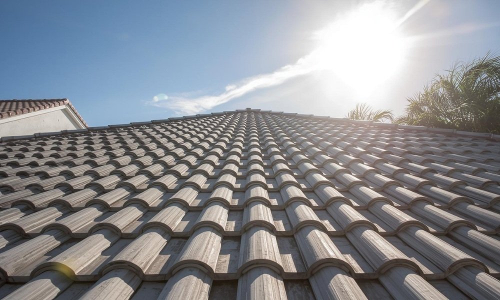 A beautiful, sun-drenched photograph of a pristine South Florida home featuring a deeply textured concrete tile roof, symbolizing long-term durability and sound investment.