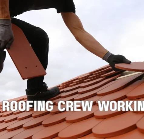 Commercial roofing crew replacing a flat commercial roof with insulation and membrane under clear skies, showing active installation on a large industrial building.